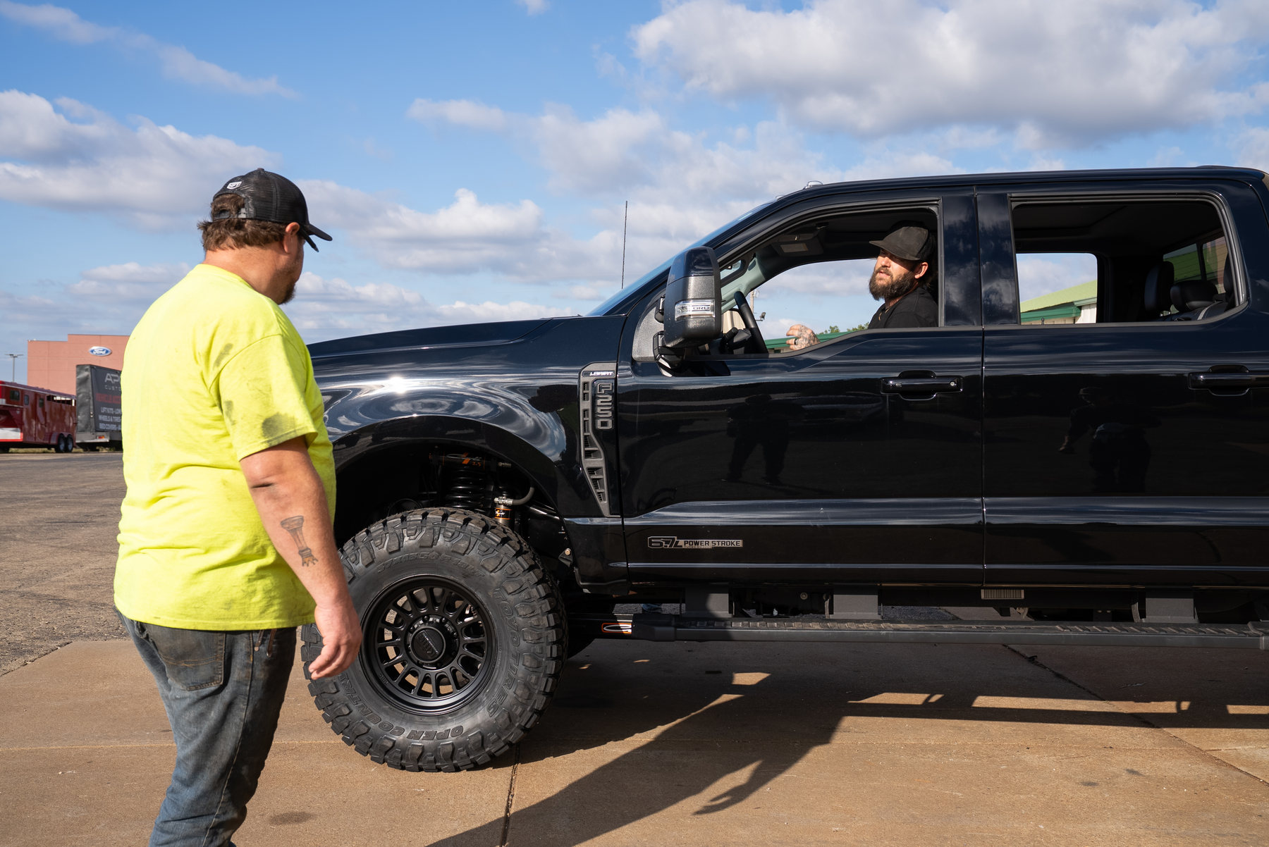 Cody beside a black Ford Super Duty while Ben sits in the driver's seat