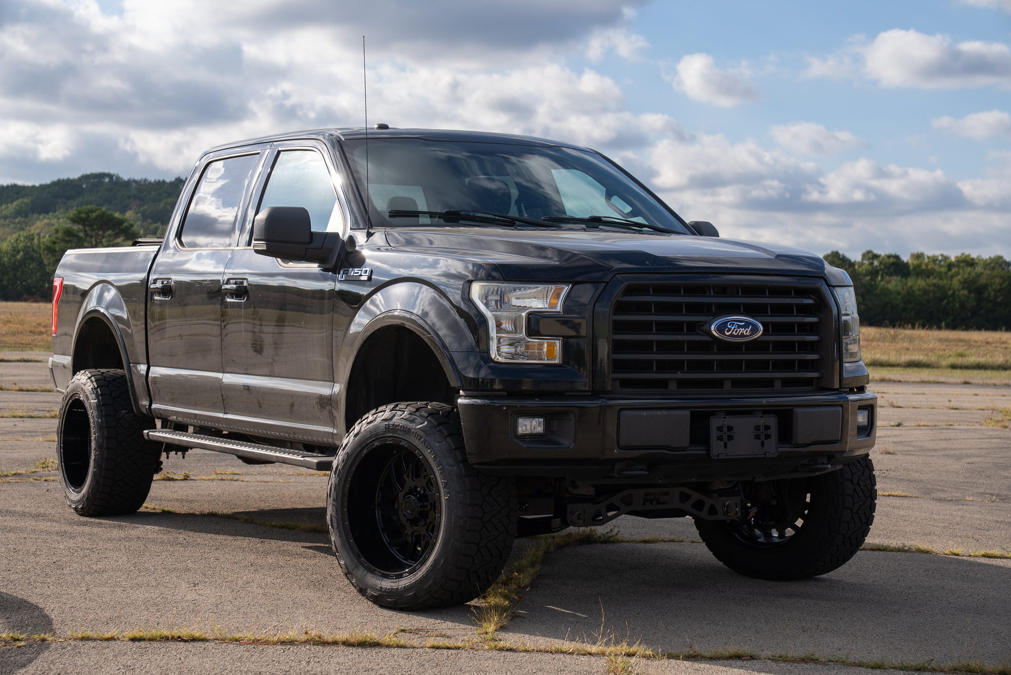 Low front-side view of the black F-150 showing its wheel and tire fitment