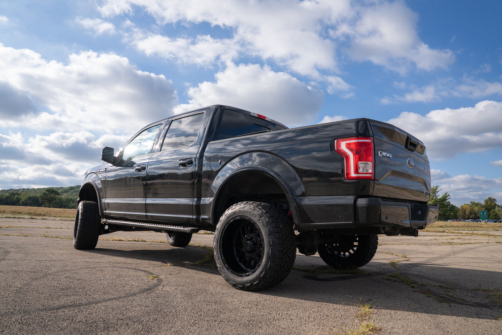 Rear three-quarter view of the same black F-150 showing its lifted stance