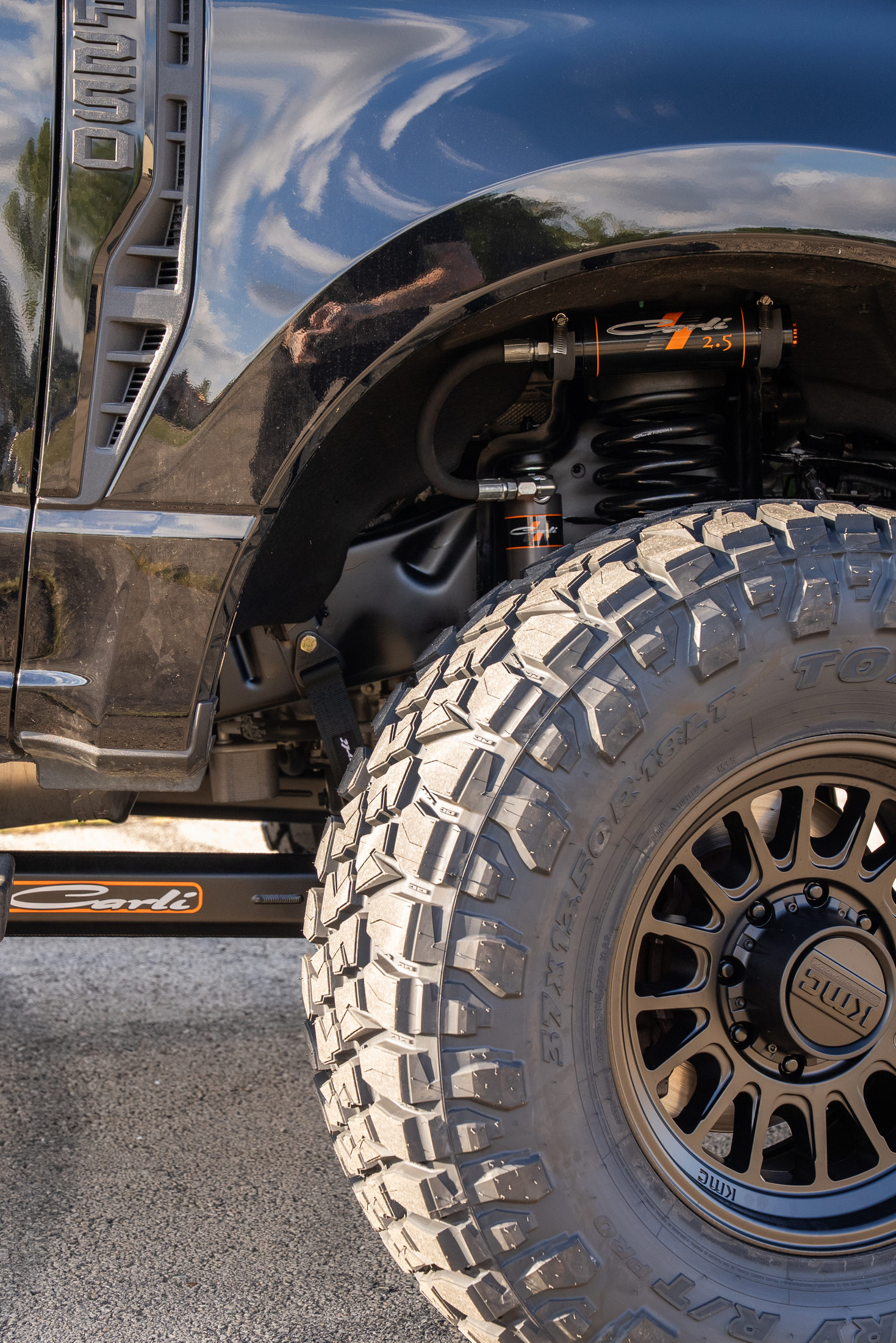 Front wheel and tire of the completed Ford F-250, with Carli suspension hardware visible inside the wheel well