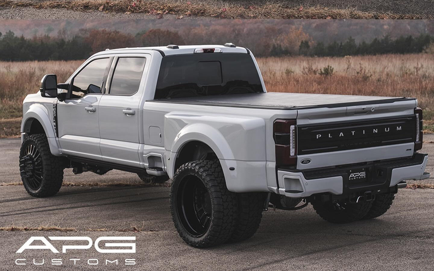 Rear three-quarter view of the same white F-450 Platinum Plus showing its paint-matched rear details and APG Customs display plate