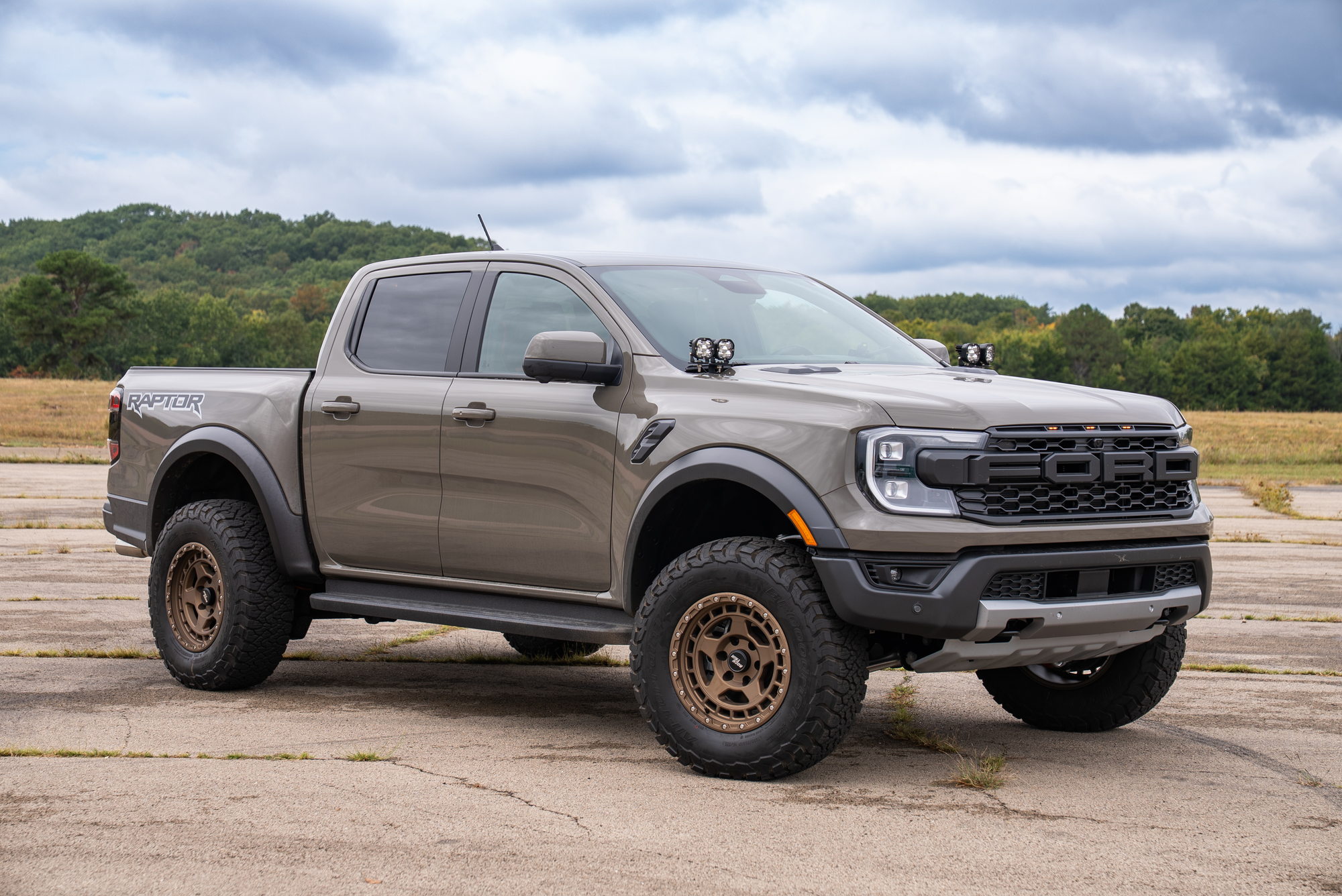 Tan Ranger Raptor with cowl-mounted pod lights, a leveled stance, and customer-supplied wheels and tires
